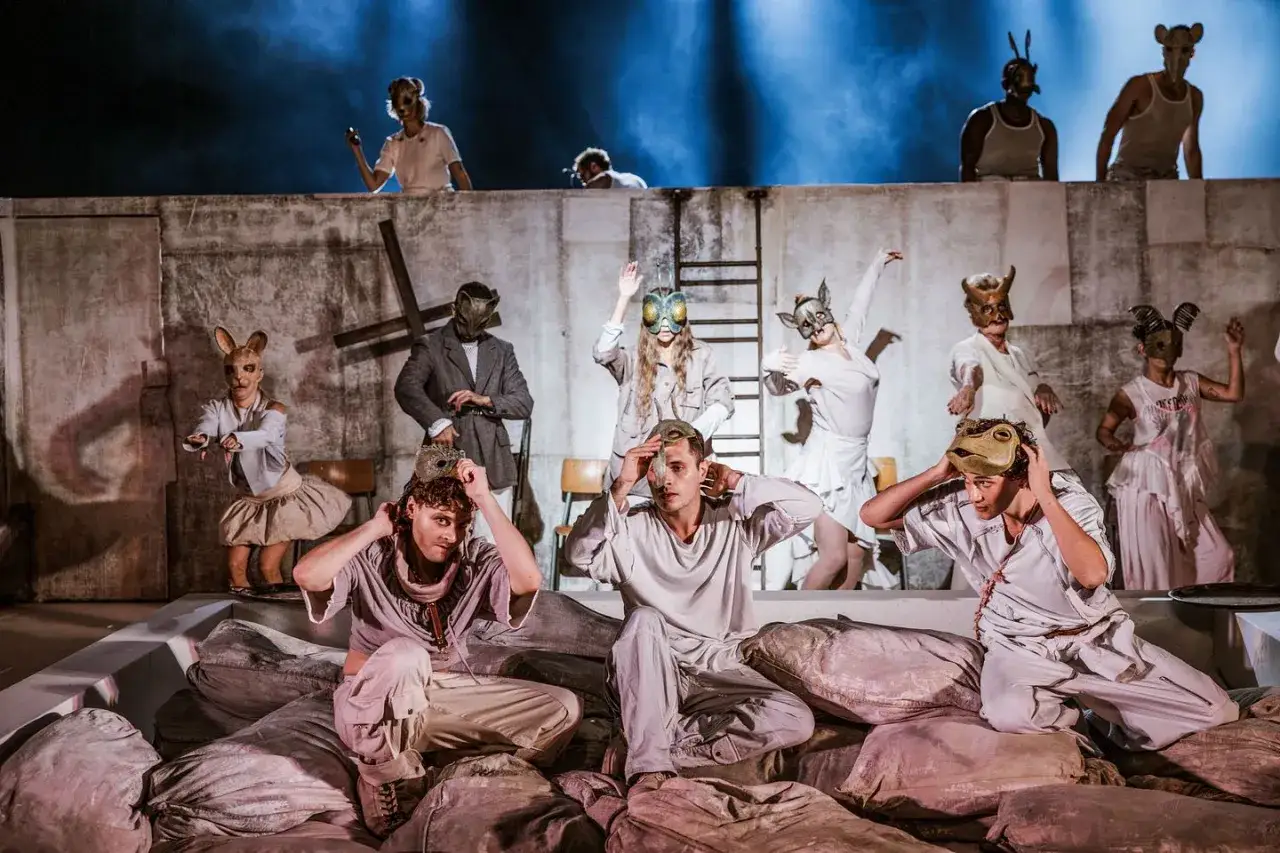 Skådespelare i djurmasker, kanske en modern tolkning av Julia och Romeo, på en scen med grova väggar och blått ljus.