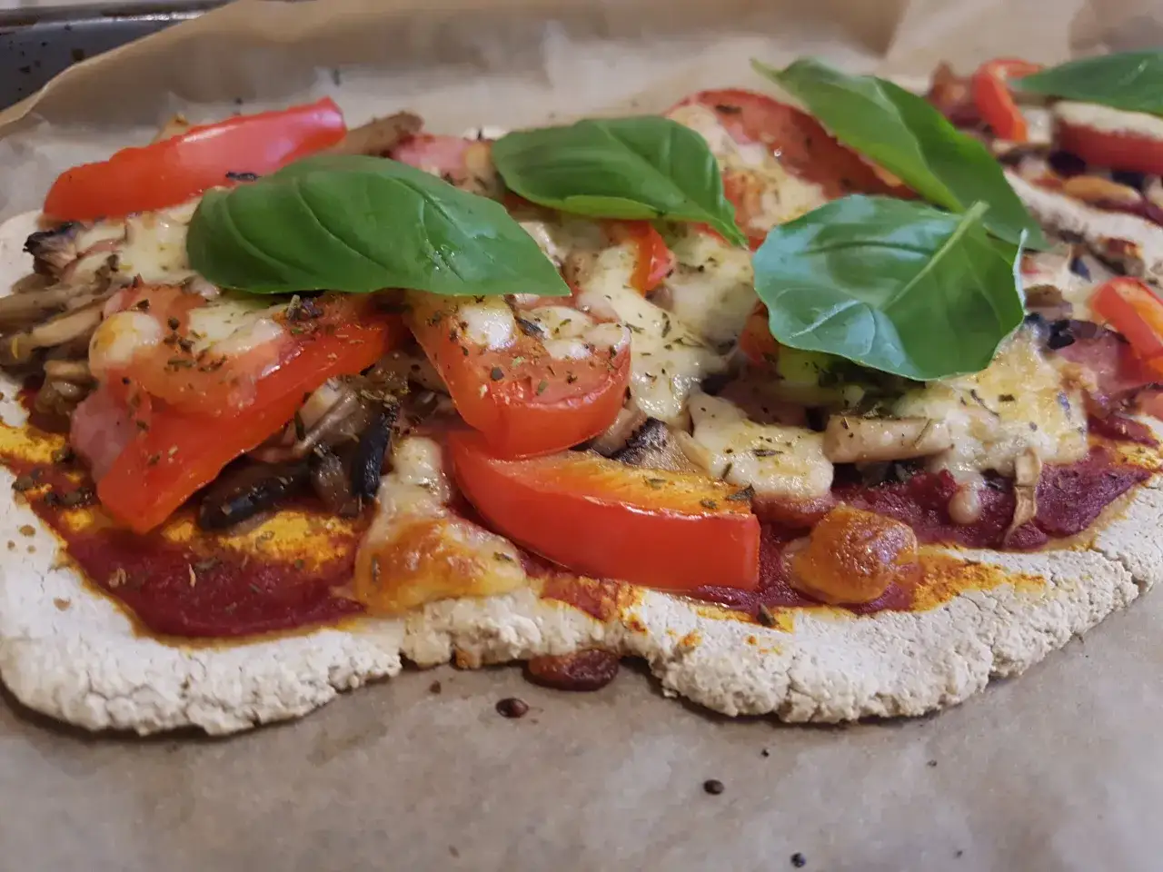Domowa pizza z niskim indeksem glikemicznym, z pomidorami, mozzarellą, pieczarkami i bazylią.