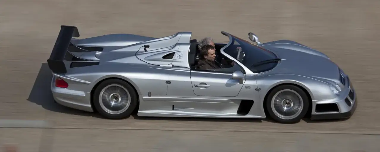 Silberner Mercedes CLK GTR Roadster mit zwei Insassen auf der Rennstrecke. Ein Blick auf den beeindruckenden Mercedes CLK GTR Preis.