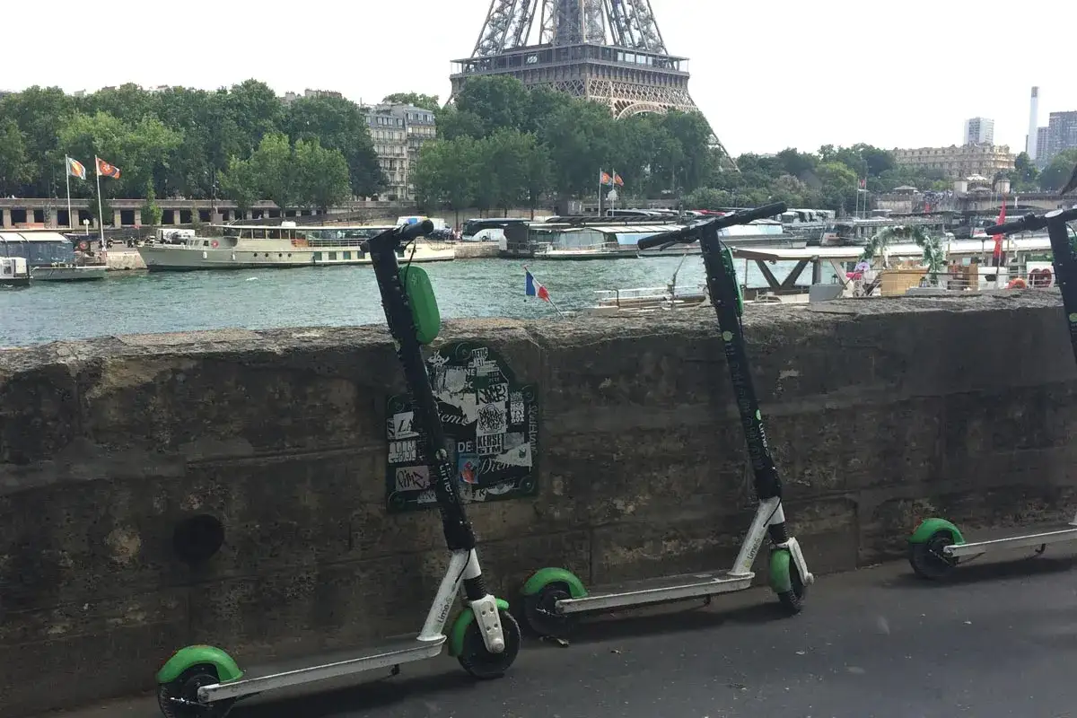 Trottinettes électriques Lime prêtes pour un parcours de 10 km en temps réel le long de la Seine, avec la Tour Eiffel en arrière-plan.
