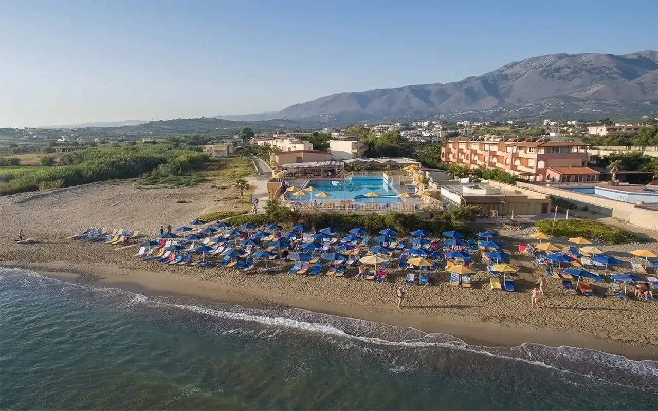 Piękna plaża Kavros Beach z mnóstwem leżaków i parasoli. W tle hotel z basenem. Idealne miejsce na wakacje, zgodnie z wieloma kavros beach opinie.