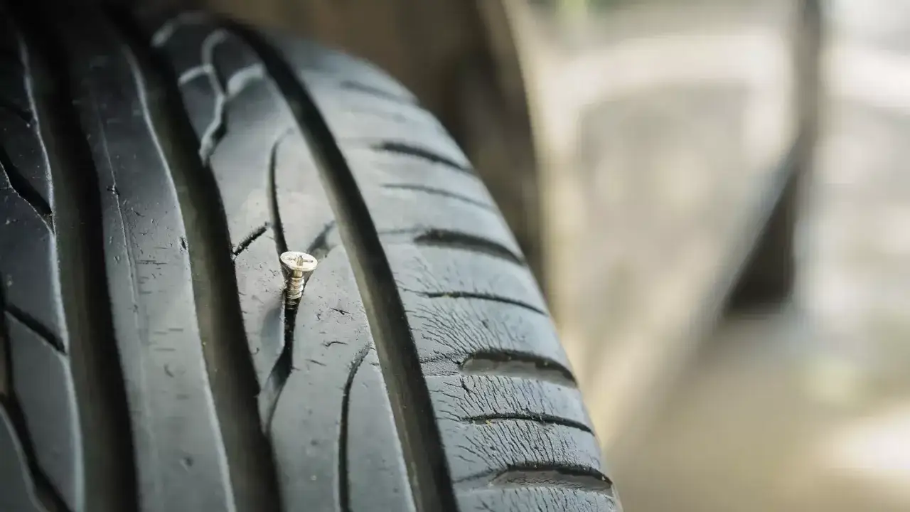 Eine Schraube steckt in einem Autoreifen. Zum Glück ist reifen flicken erlaubt, sonst wäre die Fahrt zu Ende.