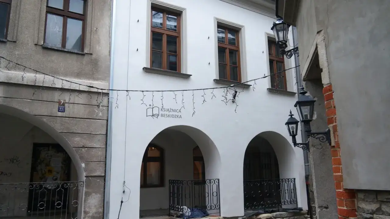 Urokliwe kamienice na rynku w Bielsku-Białej, ozdobione świątecznymi lampkami. Widać łuki arkadowe i zabytkowe latarnie.
