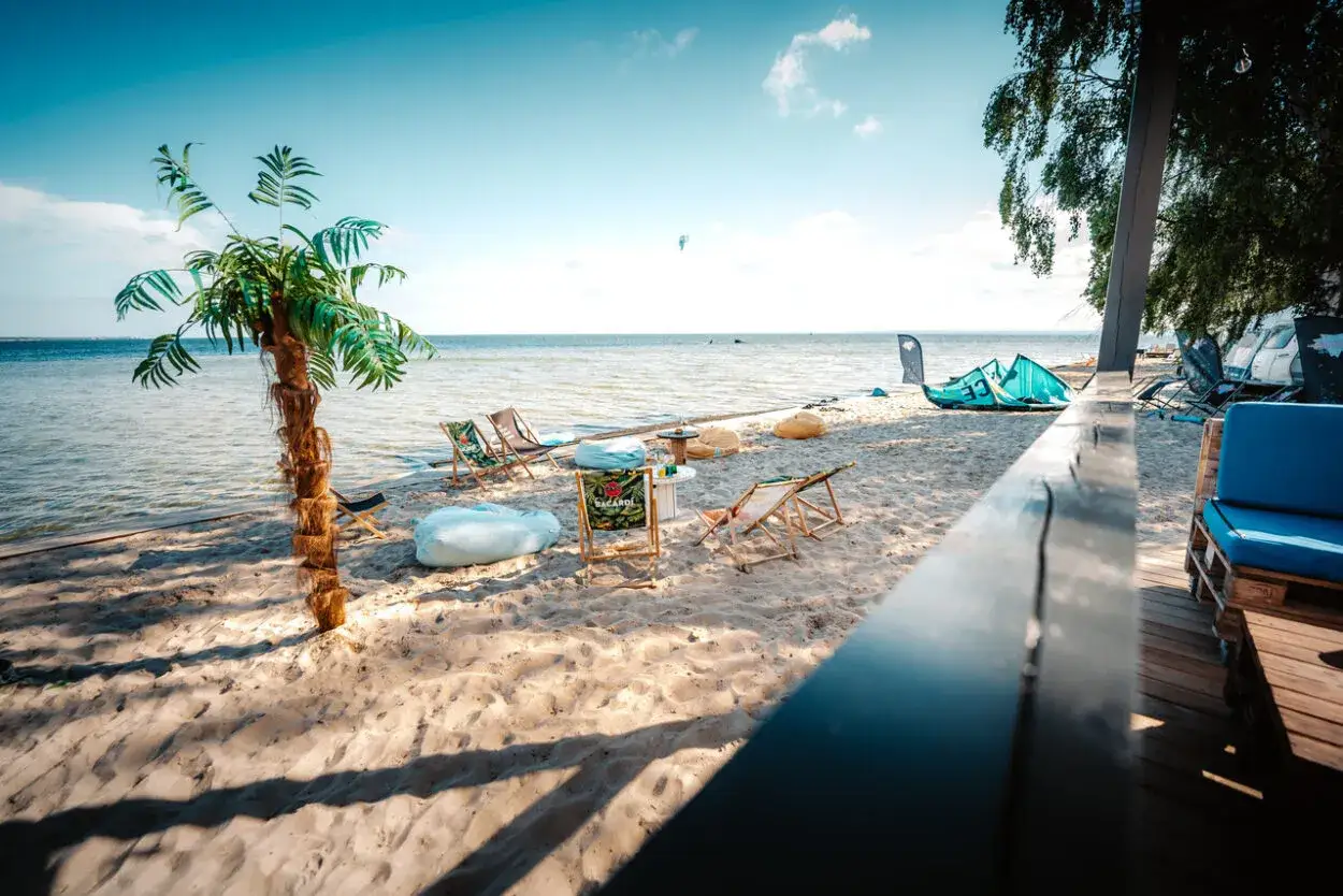 Plaża w Jastarni z leżakami i sztuczną palmą, idealne miejsce na relaks. To świetne jastarnia atrakcje dla dzieci i dorosłych.