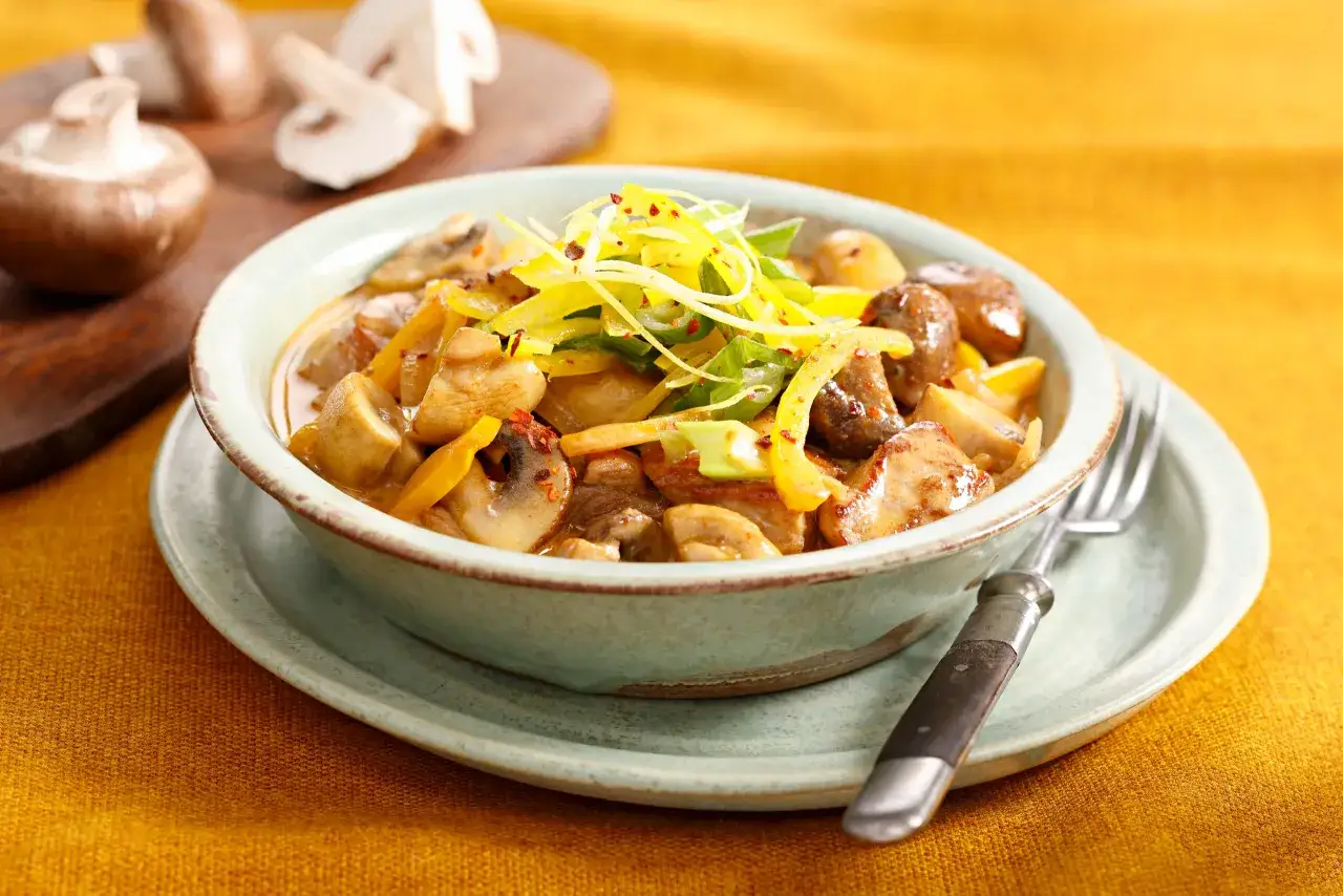 Pilzgericht in cremiger blue cheese sauce, garniert mit gelben Paprikastreifen und Fr&uuml;hlingszwiebeln.