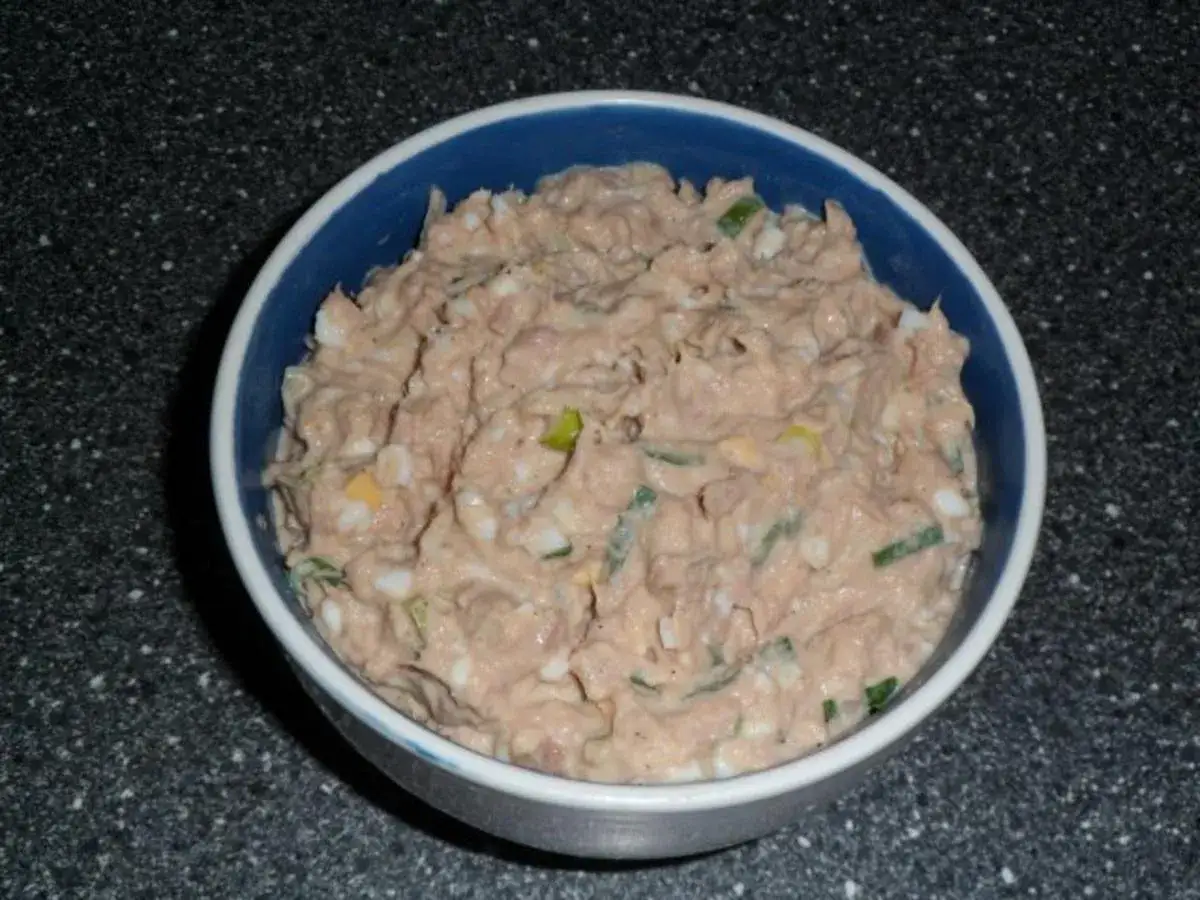 Schüssel mit cremigem Thunfischsalat, garniert mit hartgekochtem Ei und Frühlingszwiebeln. Perfekt für ein schnelles Mittagessen.