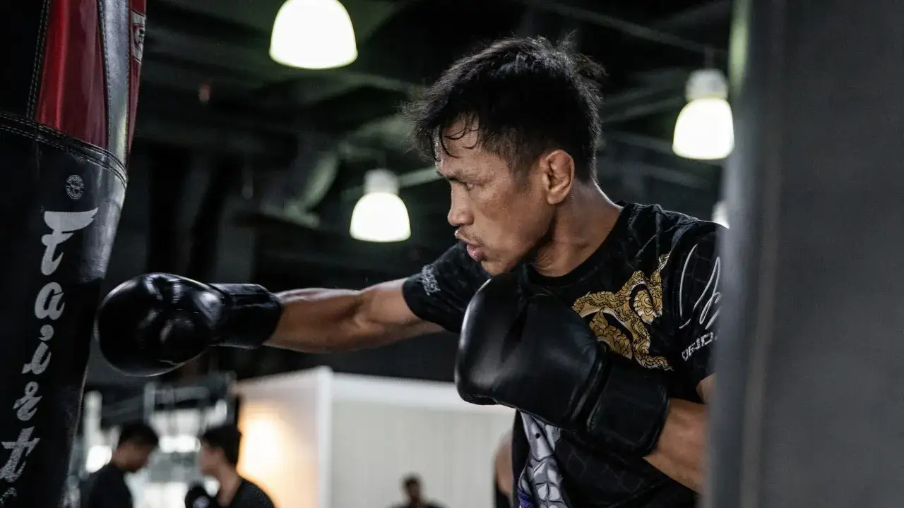 A determined pressure fighter trains with a punching bag, sweat glistening on his brow.