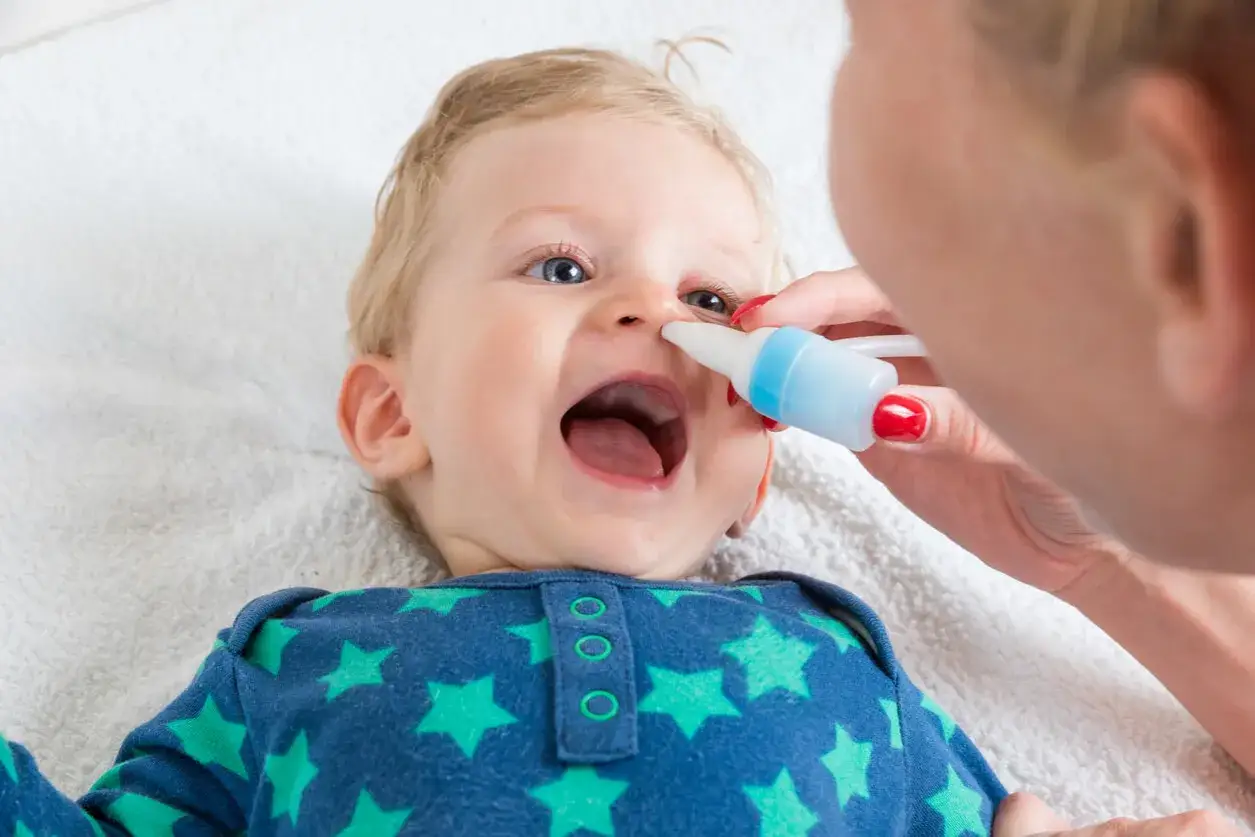Bebé con aspirador nasal. La cantidad de cuántos lavados nasales se pueden hacer a un bebé depende de su estado.