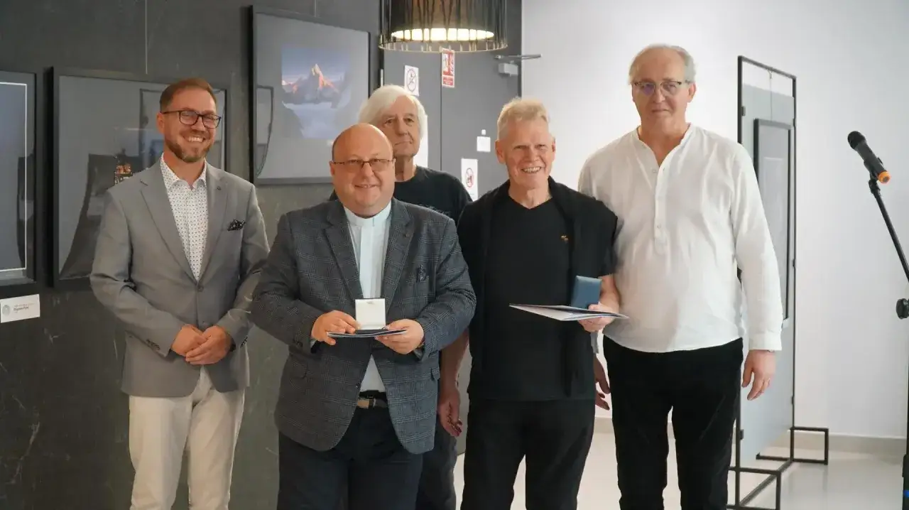Uczestnicy konkursu fotografii odbierają nagrody. Uśmiechnięci panowie pozują do zdjęcia z dyplomami i medalami.