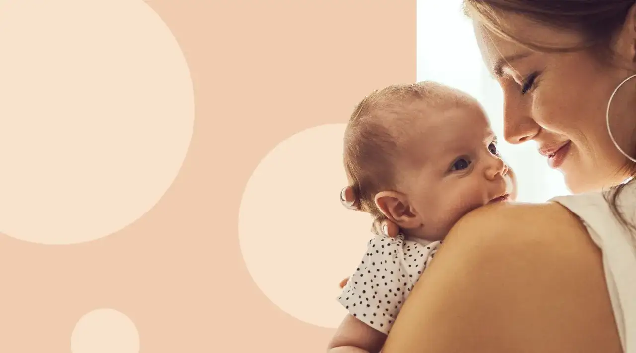 Uśmiechnięta mama tuli swoje dziecko, obserwując jego rozw&oacute;j noworodka. Delikatne spojrzenia i bliskość.