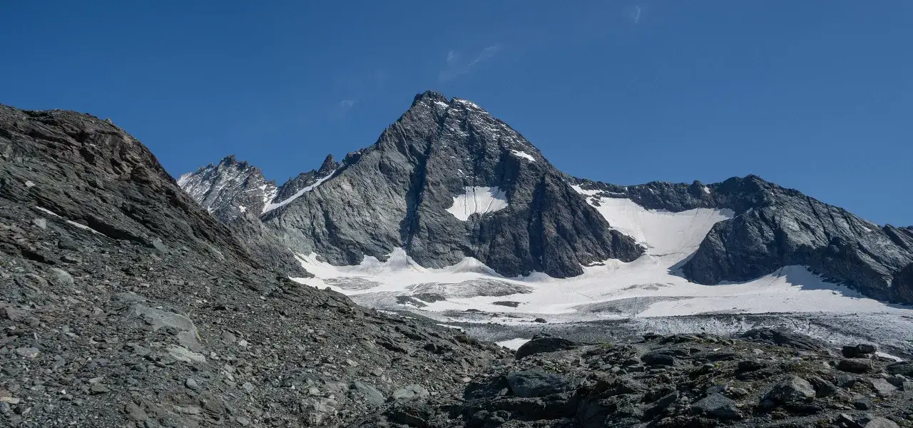 Majestatyczny najwyższy szczyt w Austrii, Grossglockner, wznosi się dumnie na tle błękitnego nieba, pokryty śniegiem i lodem.