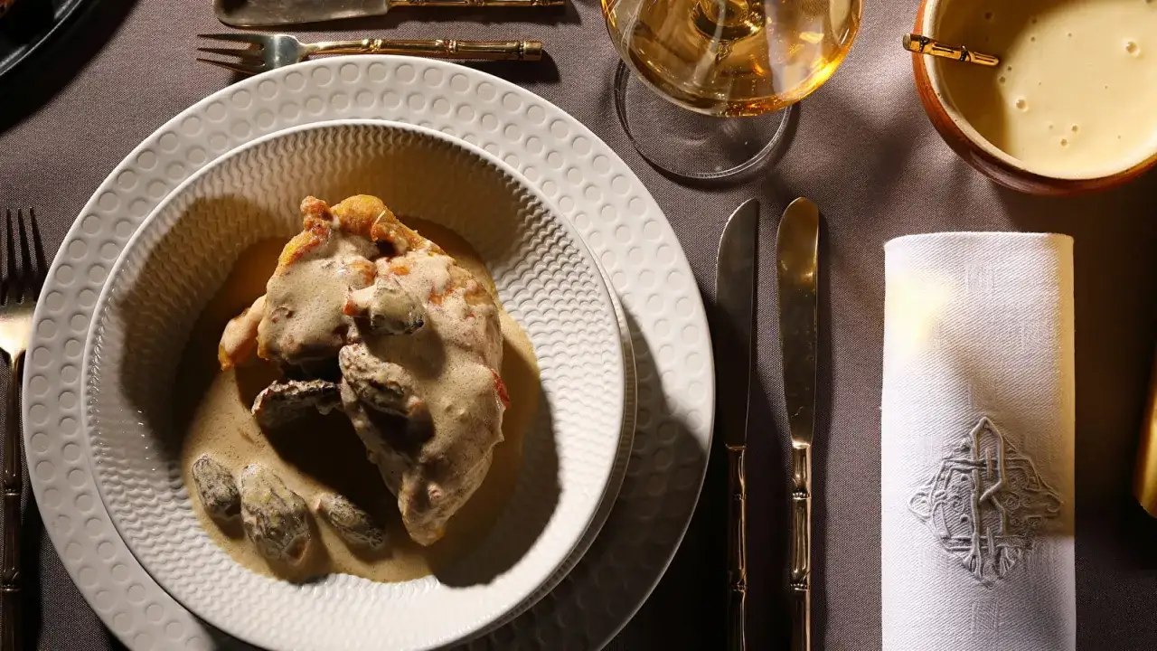 Un plat de volaille en sauce crémeuse avec des morilles, une spécialité jurassienne, servi sur une table dressée avec élégance.
