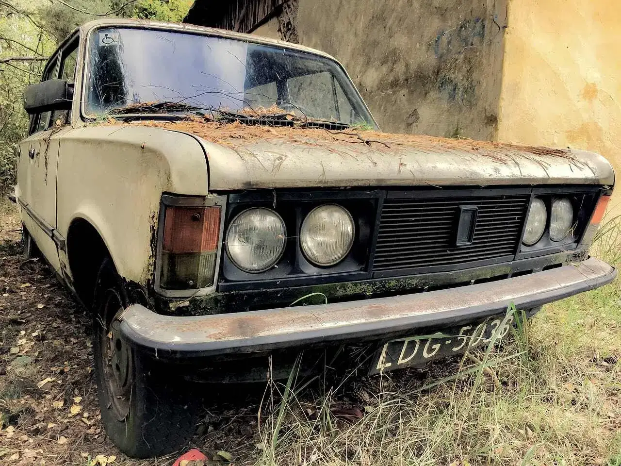 Stary Fiat 125p, jeden z klasyków polskich marek samochodów, porzucony wśród natury.