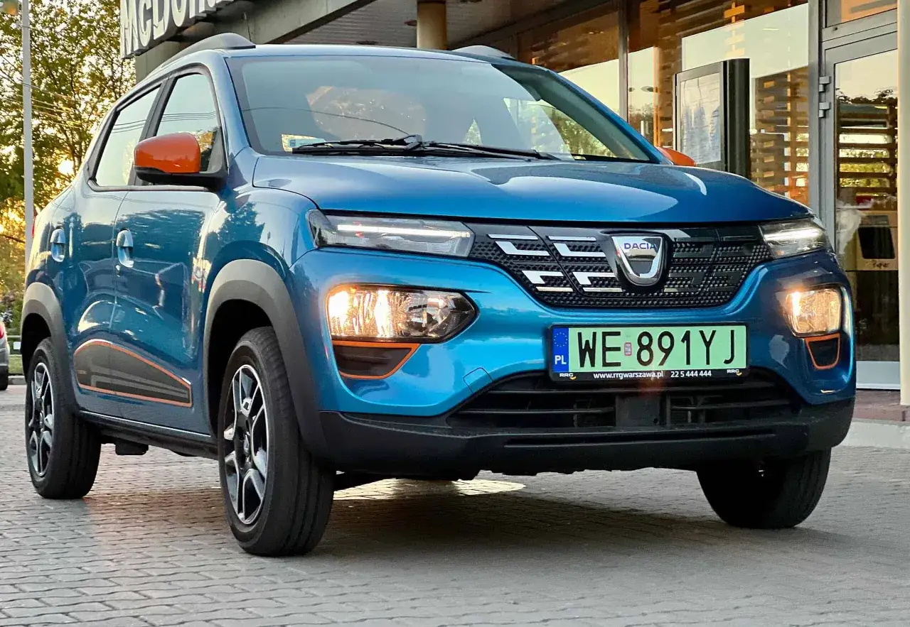 Niebieska Dacia Spring z pomarańczowymi akcentami, gotowa na długie trasy. Sprawdź jej zasięg!