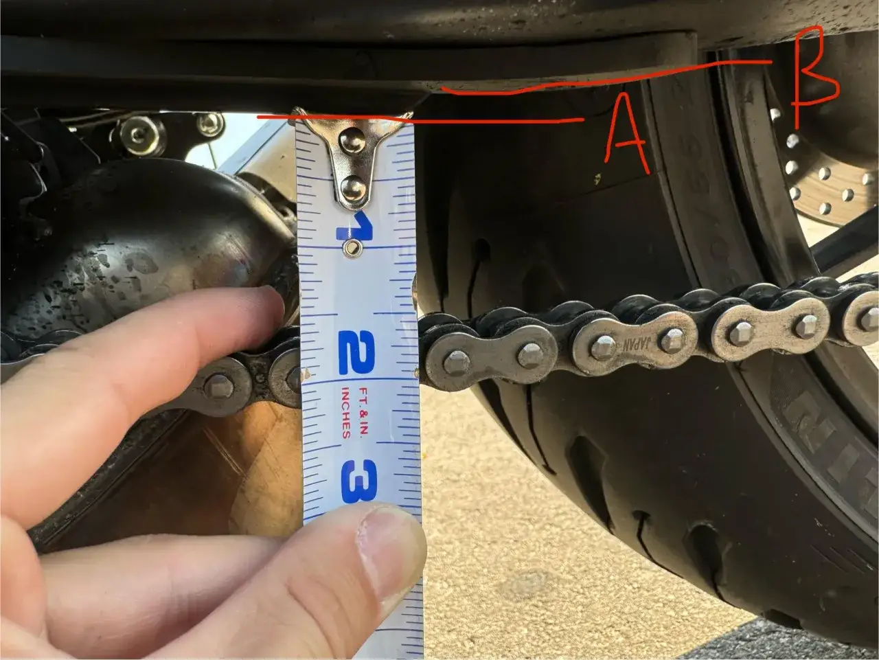 Misura la tensione della catena della moto con un righello. La catena è troppo allentata se si muove più di 2-3 cm.