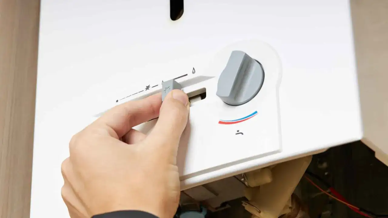 Mano che regola la manopola di uno scaldabagno a gas Bosch, forse per risolvere problemi di accensione o temperatura.