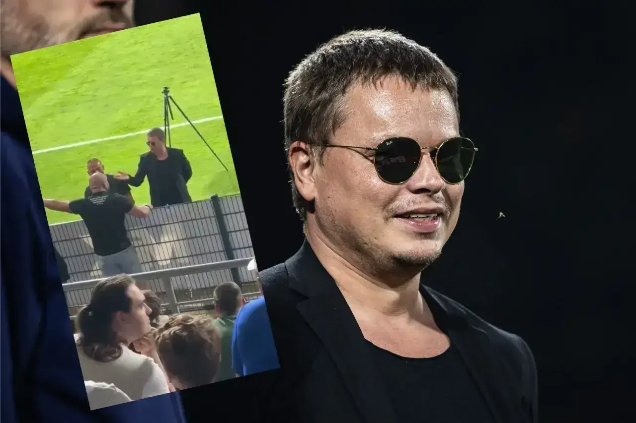 Właściciel Wisły Kraków, Tomek, w okularach przeciwsłonecznych, na tle stadionu. W tle widać fragment boiska i kibiców.