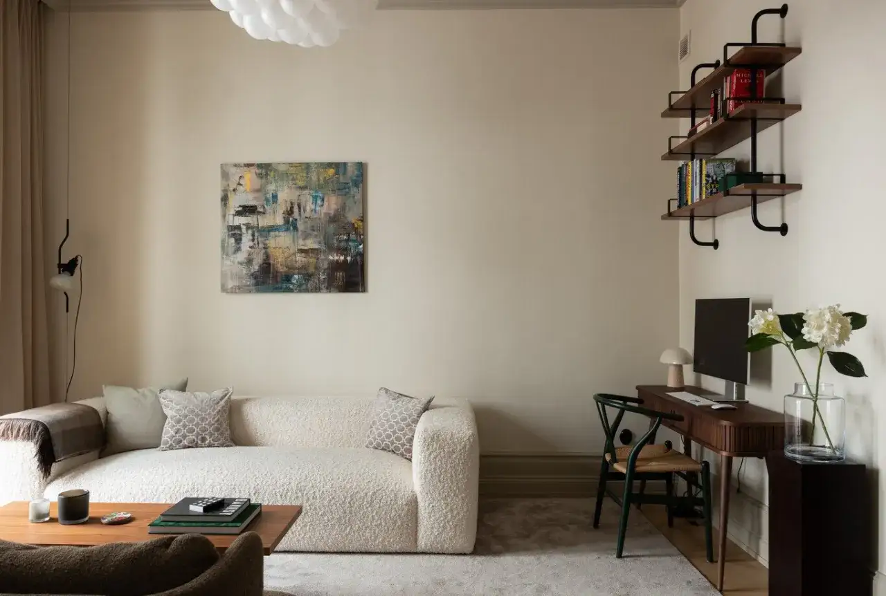 Soggiorno con divano boucl&eacute; bianco, tavolino in legno e un perfetto **abbinamento colori crema** nelle pareti e nei tessuti.