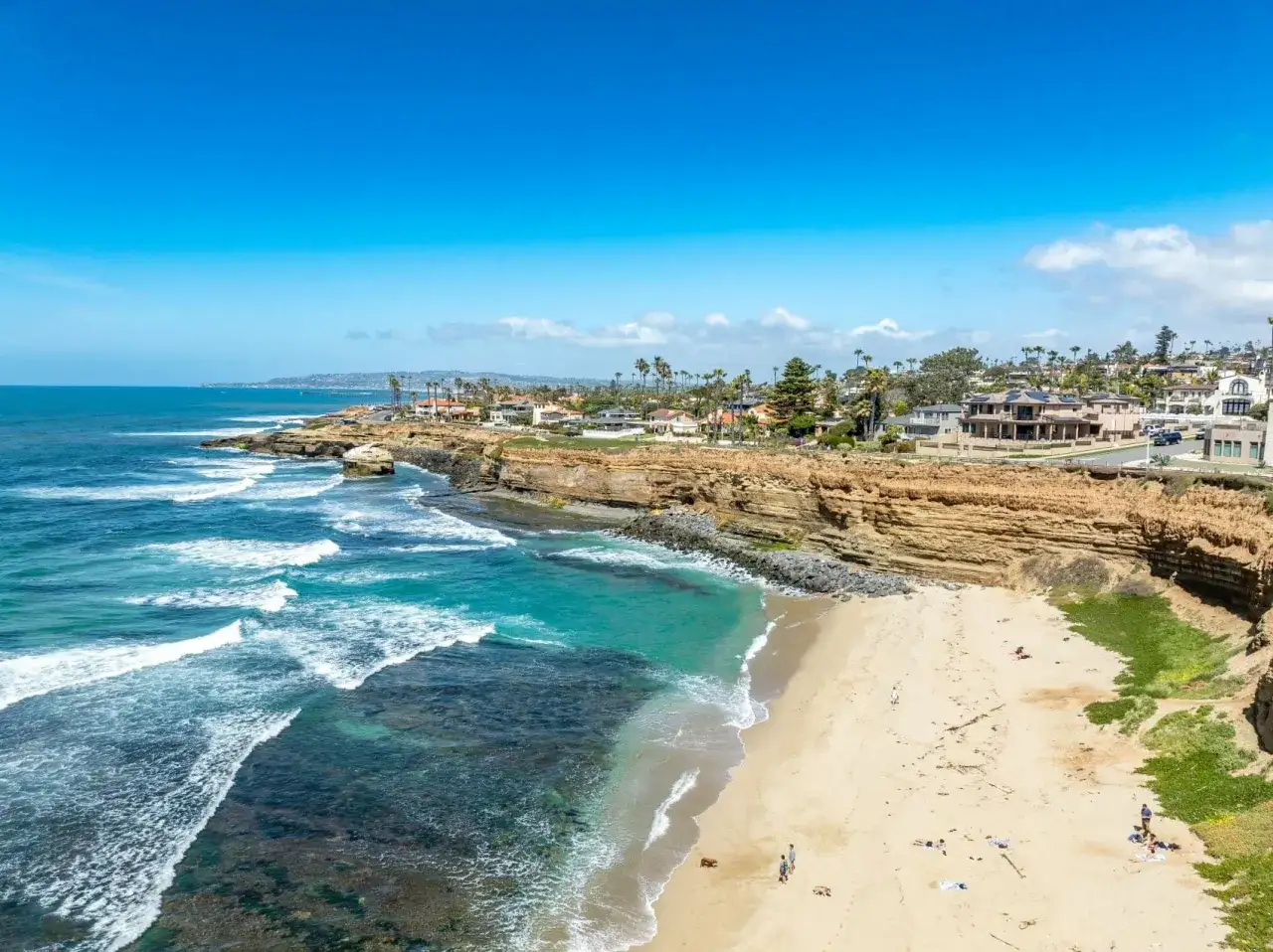 Traumhafte Küste bei San Diego mit türkisfarbenem Wasser, Sandstrand und Villen auf den Klippen.