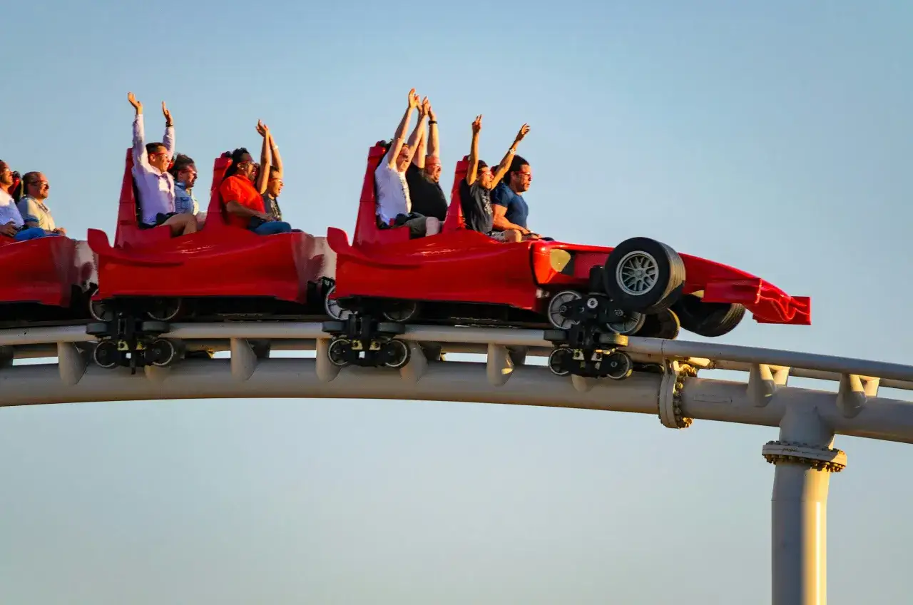 Ludzie z rękami w górze na czerwonym wagoniku kolejki górskiej w Dubaju, Ferrari World.