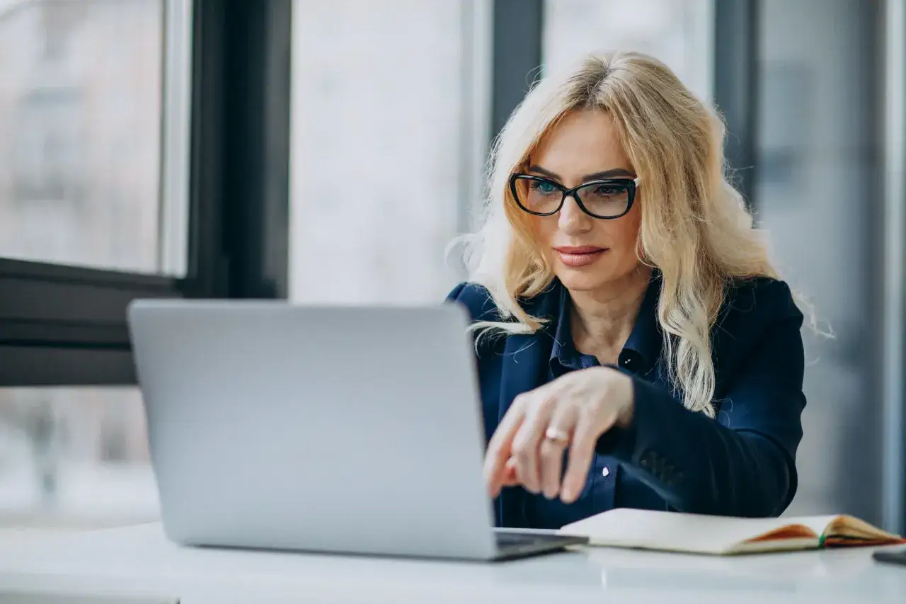 Kobieta w okularach pracuje przy laptopie, szukając informacji o zus renta rodzinna po mężu.