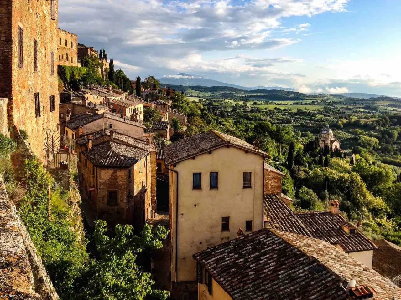 Panoramica di borghi toscana in treno, con case in pietra e colline verdi.