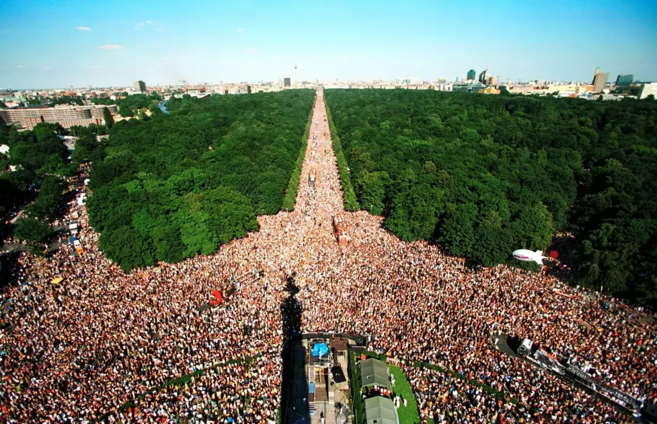 Multitudinaria celebración del Love Parade Berlin, con miles de personas disfrutando en un día soleado.