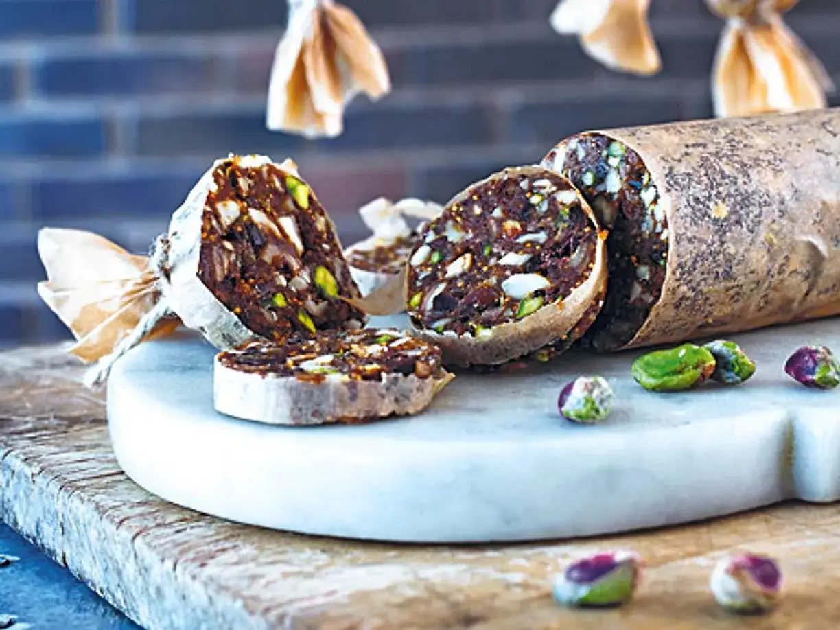 Chokladsalami med nötter och torkad frukt, skuren i skivor och serverad på en marmorplatta.