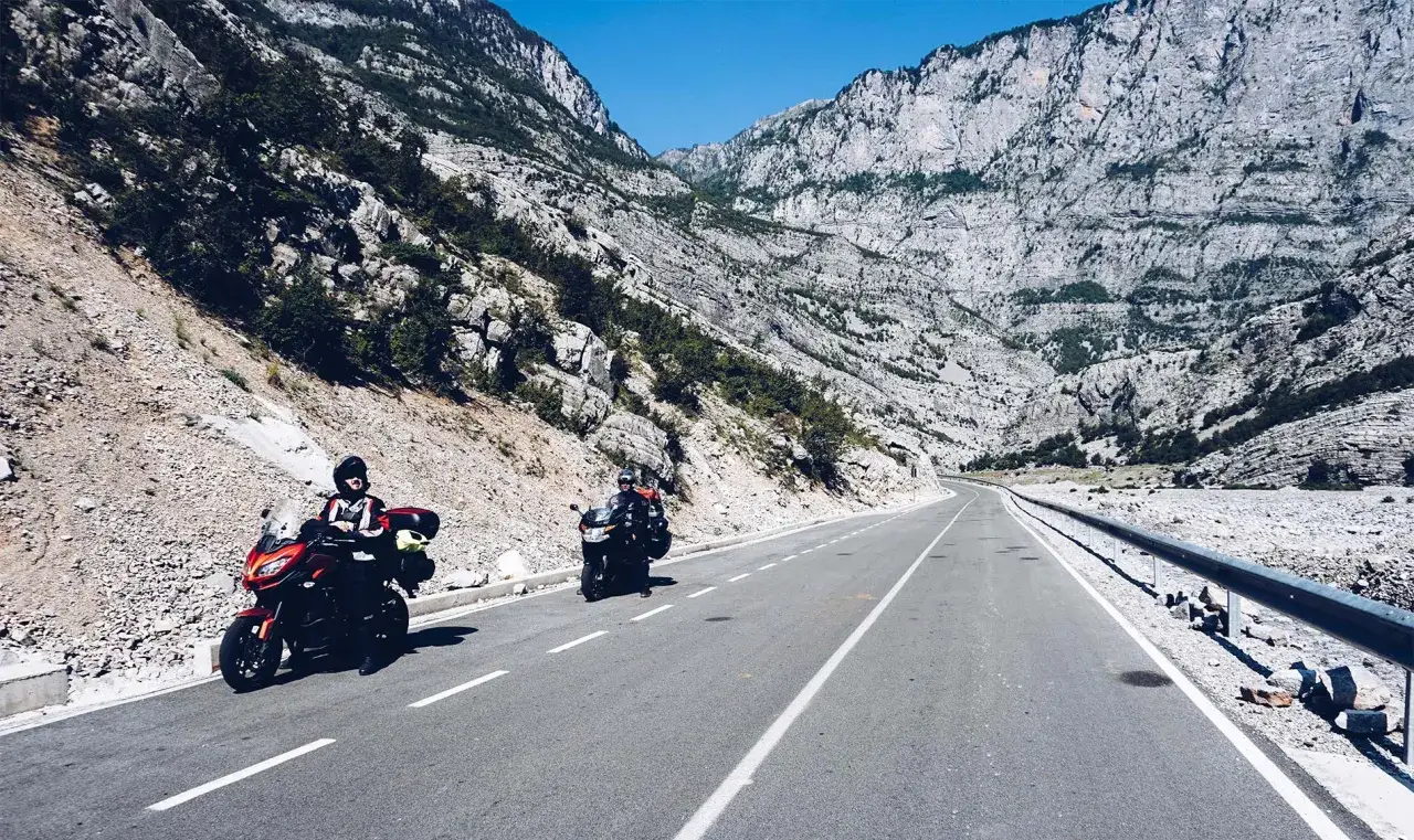 Motocykliści przemierzają malowniczą drogę w Albanii, mijając skaliste zbocza i ukryte bunkry z czasów komunizmu.