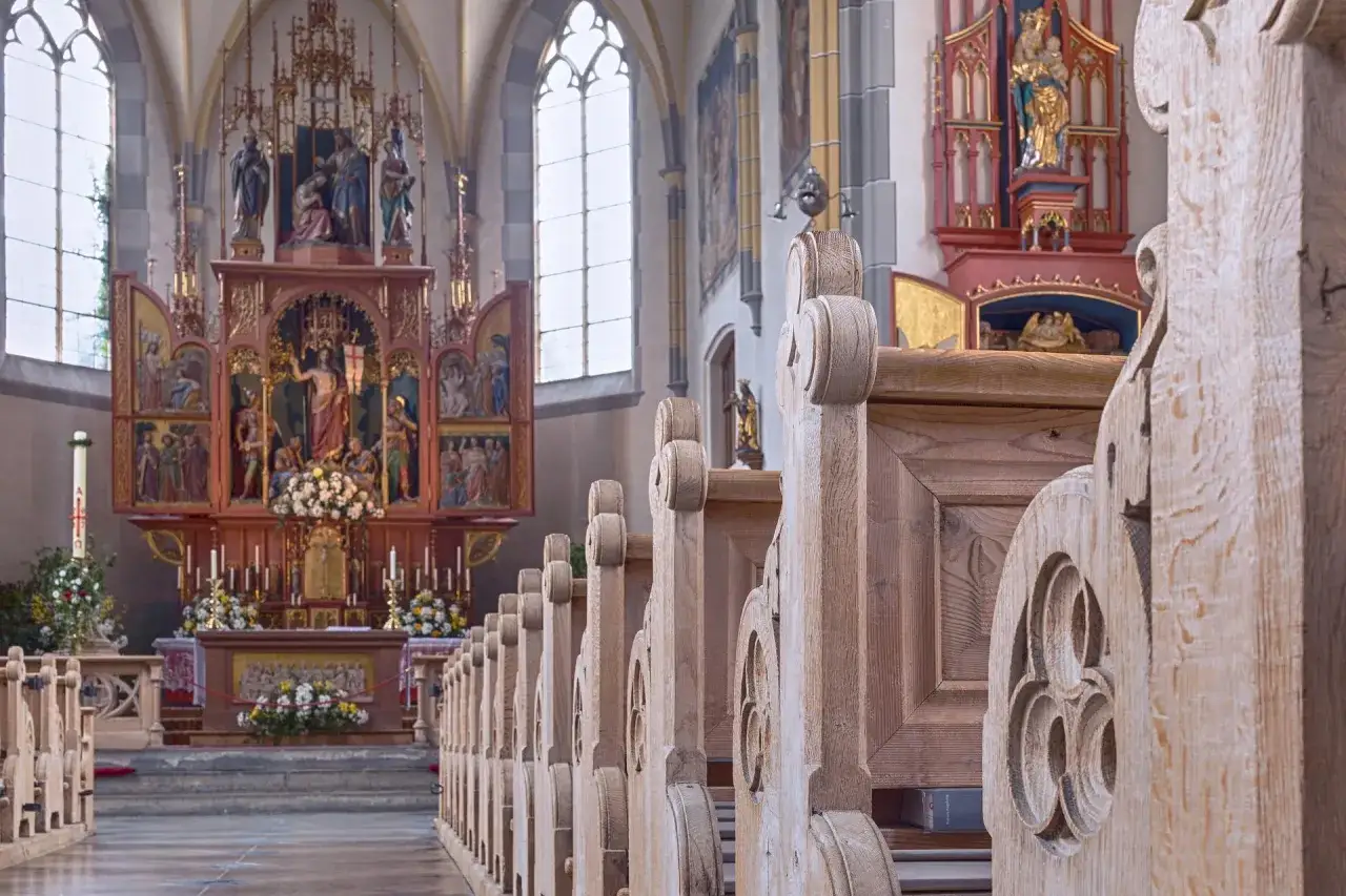 Drewniane ławki w kościele św. Jana w Warszawie prowadzą do ołtarza z pięknymi rzeźbami.