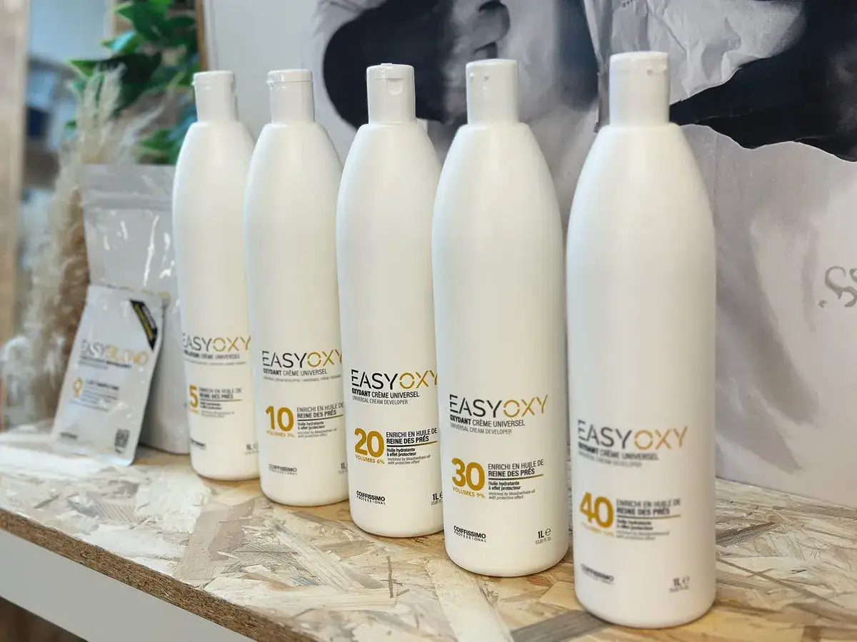 Cinq bouteilles d'oxydant cr&egrave;me universel, montrant la diff&eacute;rence entre oxydant et r&eacute;v&eacute;lateur pour la coloration.