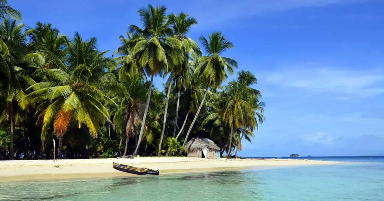 Rajska plaża na San Blas z palmami, chatką i łodzią na turkusowej wodzie.