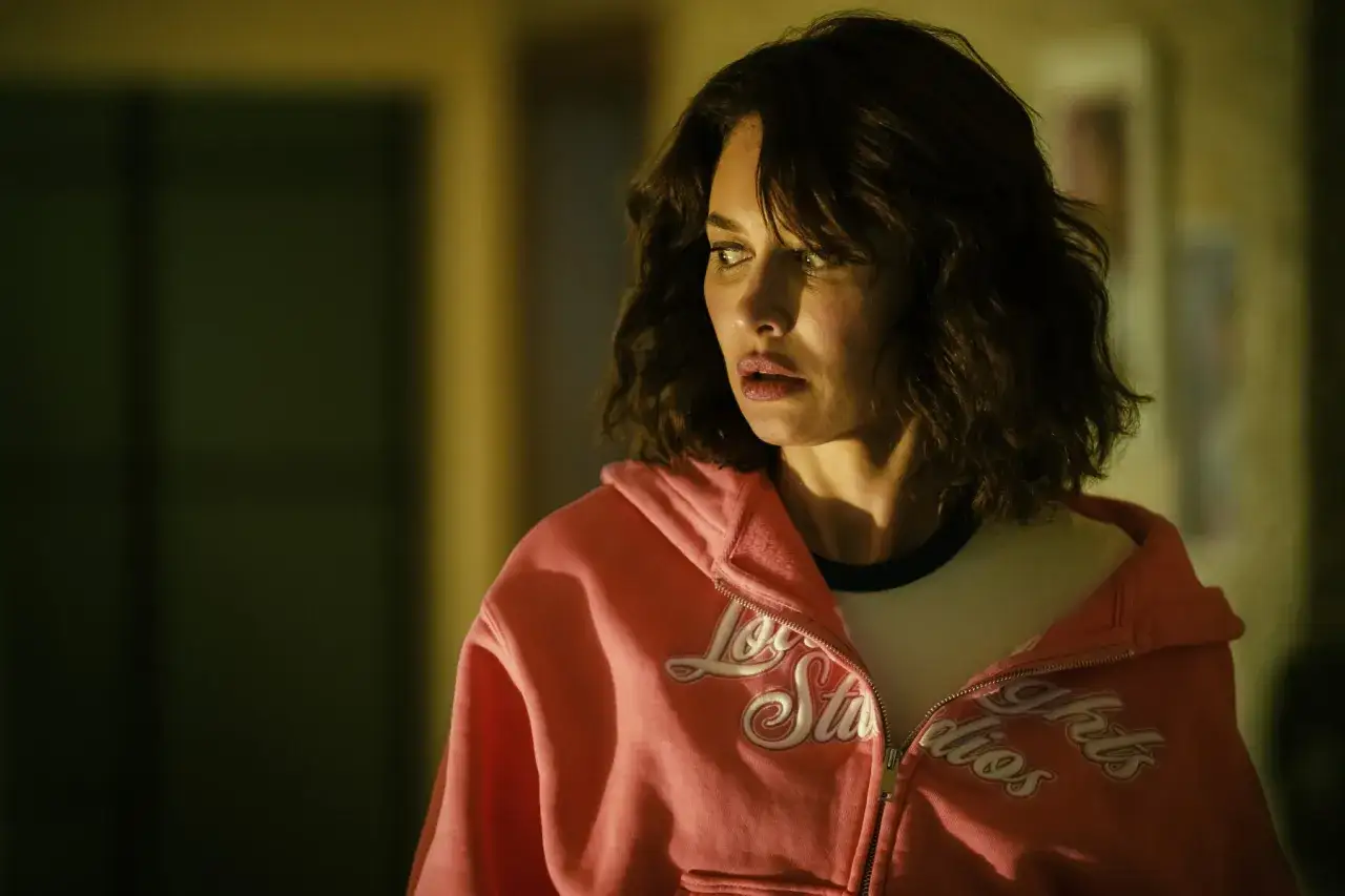 En kvinna med oroligt uttryck, kl&auml;dd i en rosa hoodie, f&aring;ngad i ett &ouml;gonblick av en psykologisk thriller.