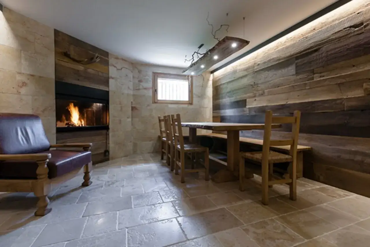 Un angolo accogliente con camino acceso, poltrona in pelle e tavolo in legno massello. Perfetto per idee taverna rustica.
