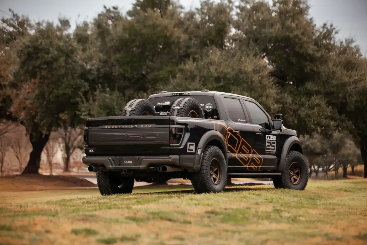 Czarny Ford F-150 Raptor z zapasowymi kołami na pace, gotowy na terenowe przygody.