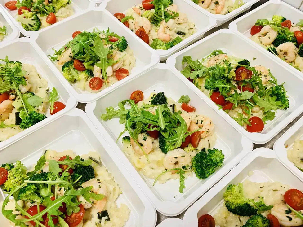 Pyszne dania bez glutenu i laktozy: krewetki, brokuły, pomidorki i rukola na kremowym risotto. Idealne na zdrowy posiłek.