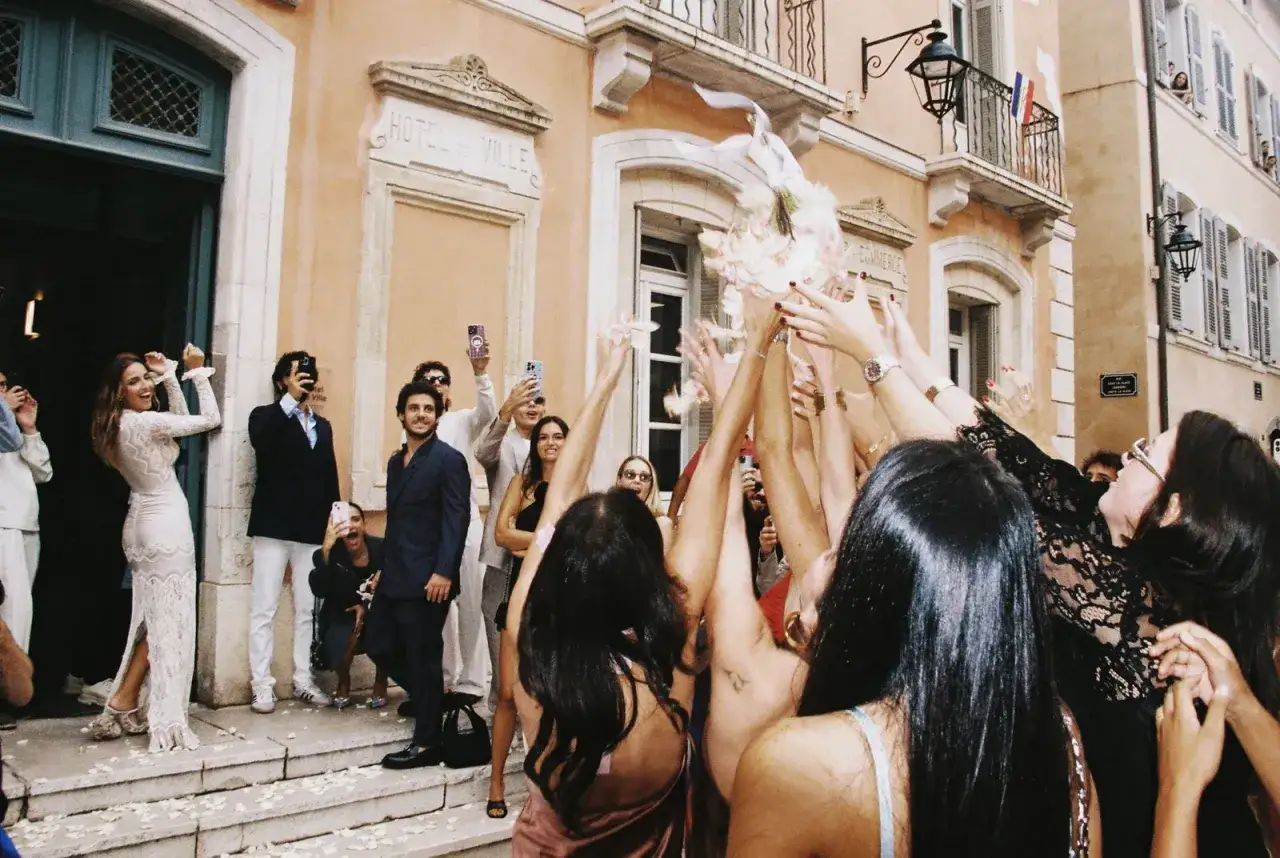 Des mains lancent des pétales et un bouquet, célébrant un **tradition mariage francais** devant l'Hôtel de Ville.