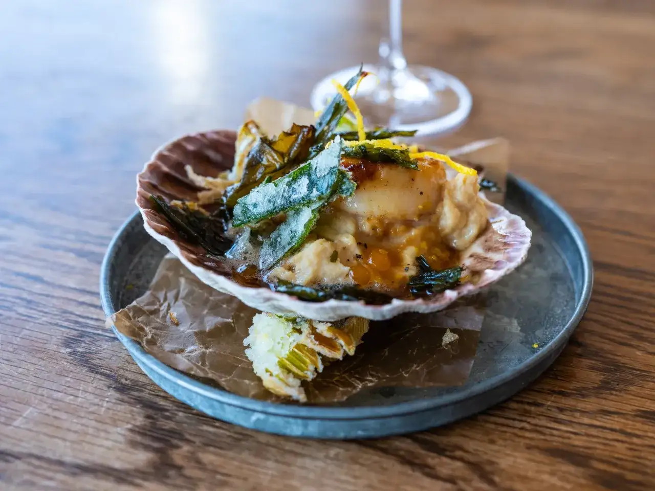 En läcker pilgrimsmussla i sitt skal, en av många fantastiska saker att göra i Göteborg. Serverad med krispiga grönsaker och en gyllene sås.