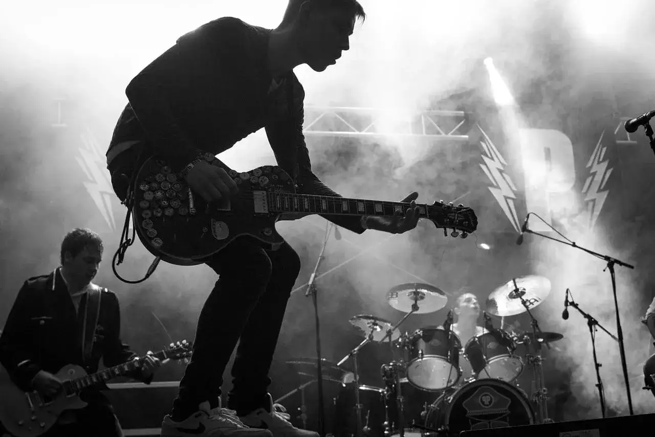 Zespół grający indie pop na scenie, w dymie i świetle.