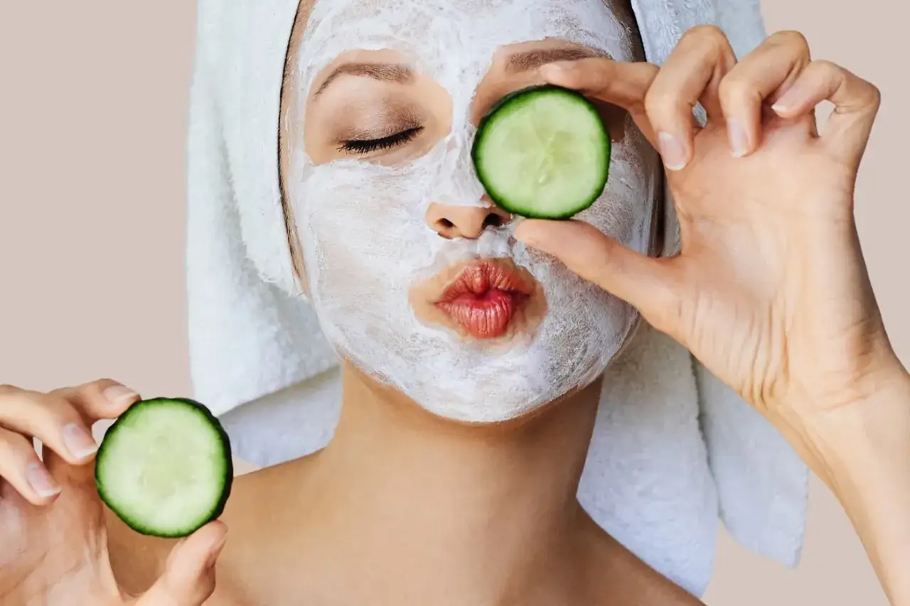 Mujer con mascarillas caseras para la cara y rodajas de pepino en los ojos.