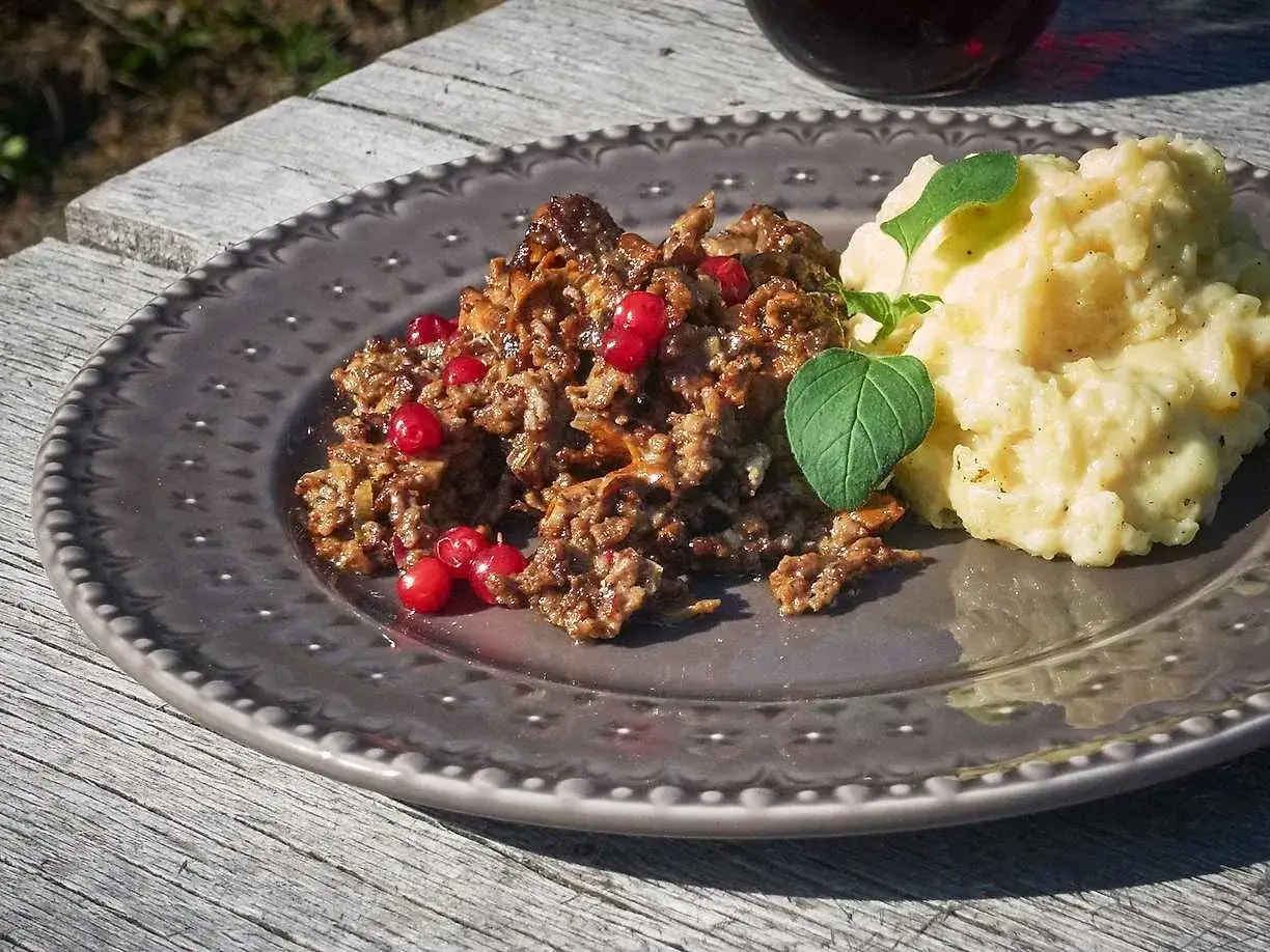 En tallrik med renskav, lingon och potatismos. Ett härligt renskav recept för en smakrik måltid.