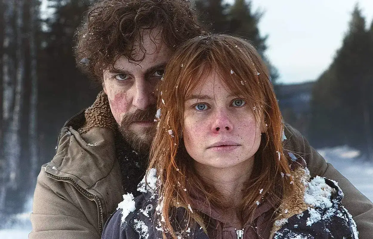Två personer i snöig skog, en kvinna med rött hår och en man med skägg. Känslan är dramatisk, som i en svensk deckare serie.