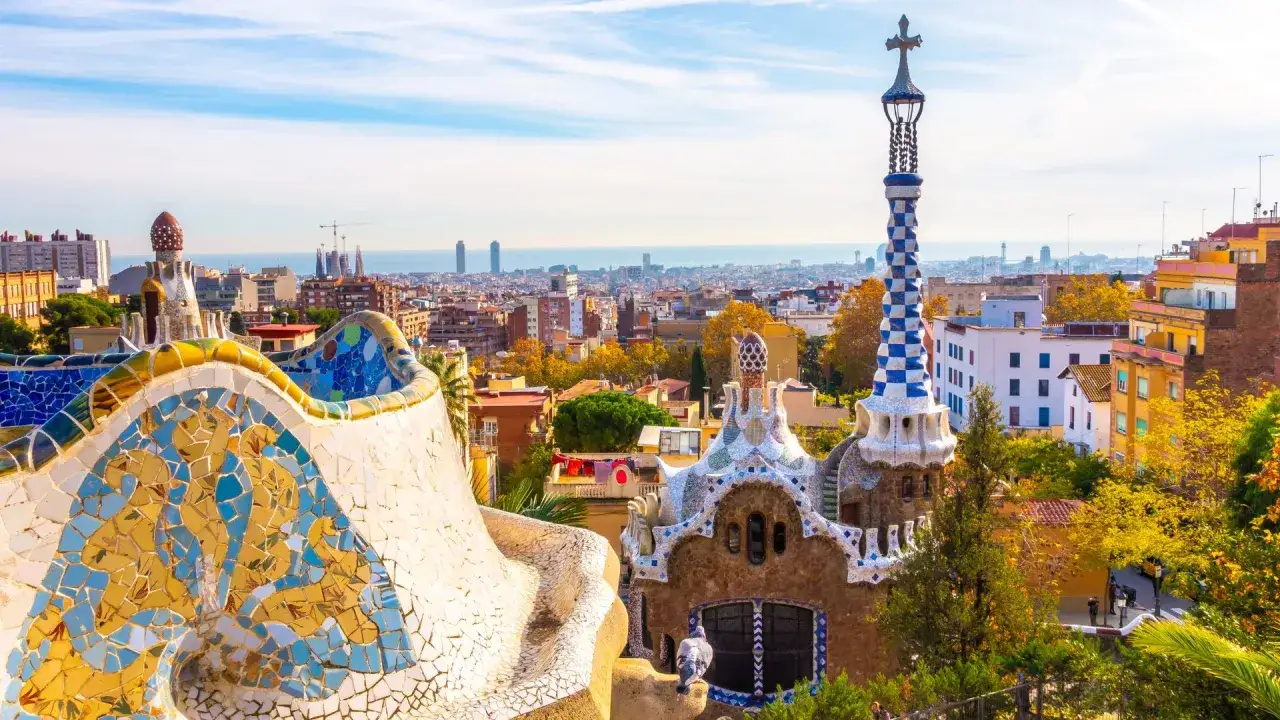 Kolorowe mozaiki Parku Güell i charakterystyczne budowle na tle Barcelony. Sprawdź park guell godziny otwarcia i zaplanuj wizytę!