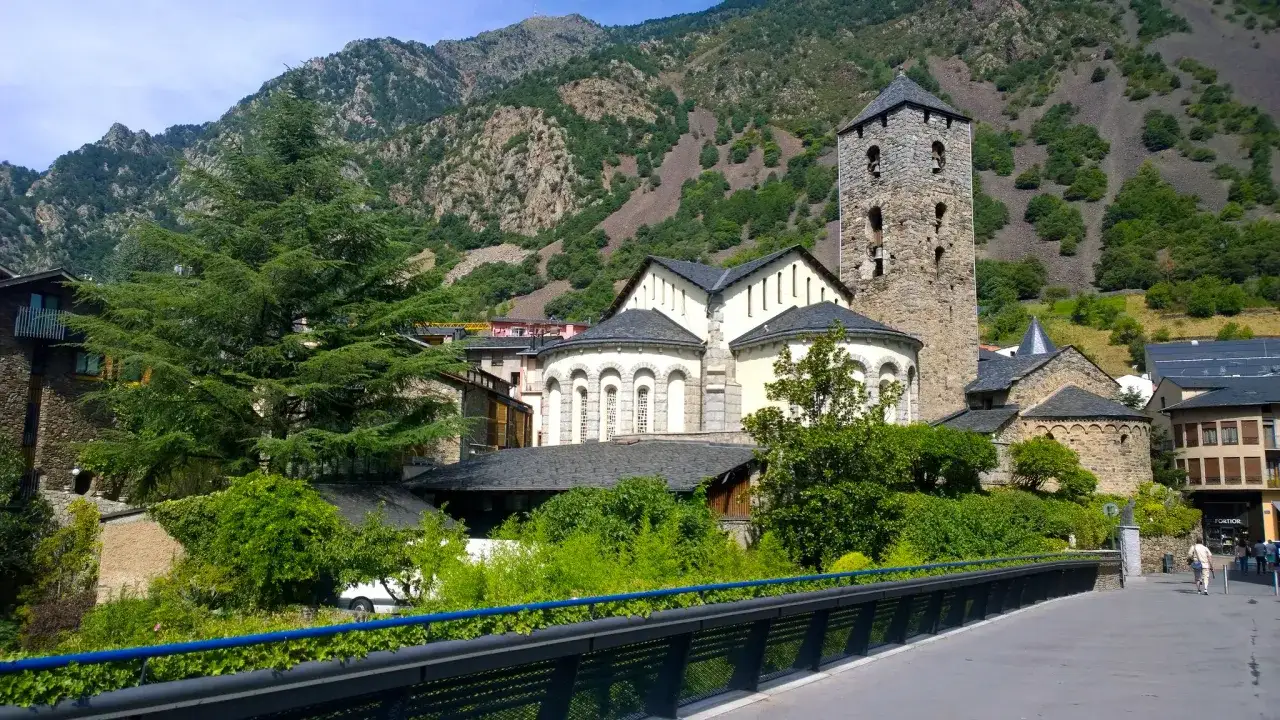 La parroquia de Escaldes-Engordany, con su torre rom&aacute;nica, se alza majestuosa entre monta&ntilde;as verdes y frondosa vegetaci&oacute;n.