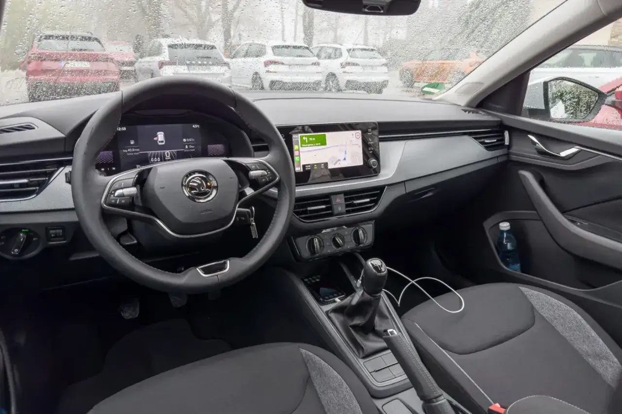 Wnętrze Skoda Scala 2024: kierownica, cyfrowe zegary i ekran multimediów z nawigacją. Widok z miejsca kierowcy na desce rozdzielczej.