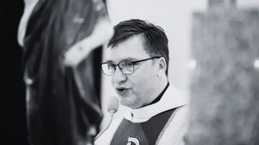 ksiądz przy biurku z dokumentami finansowymi