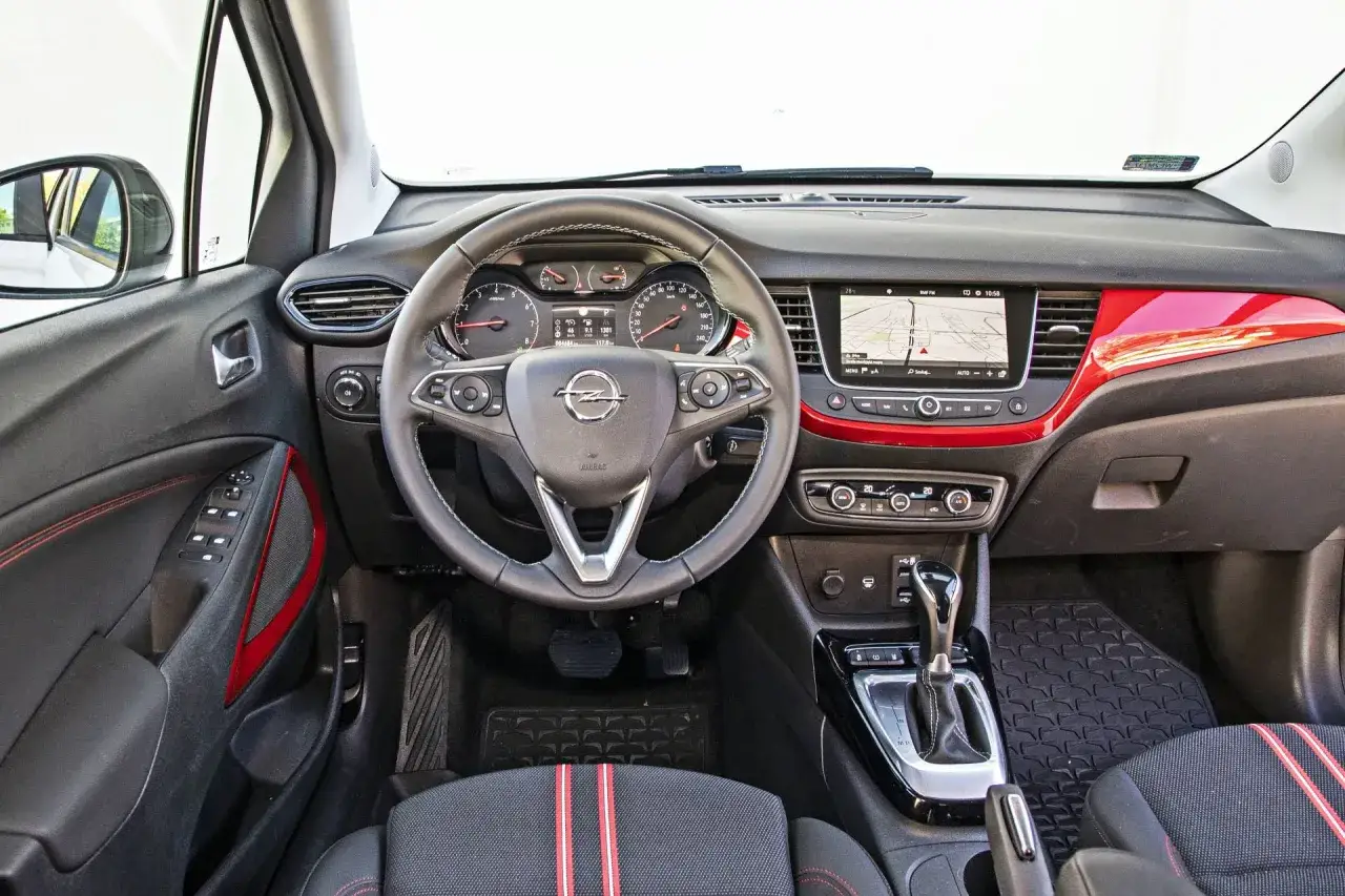 Wnętrze Opla Crossland z ekranem multimedialnym i czerwoną listwą. Sprawdź opel crossland cena i wyposażenie.