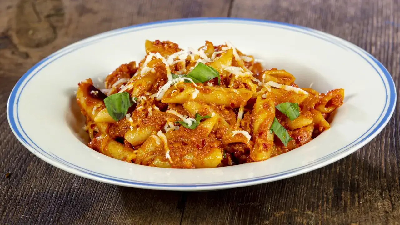 Penne al sugo piccante di nduja, guarnite con parmigiano e basilico fresco. Un piatto che scalda il cuore.