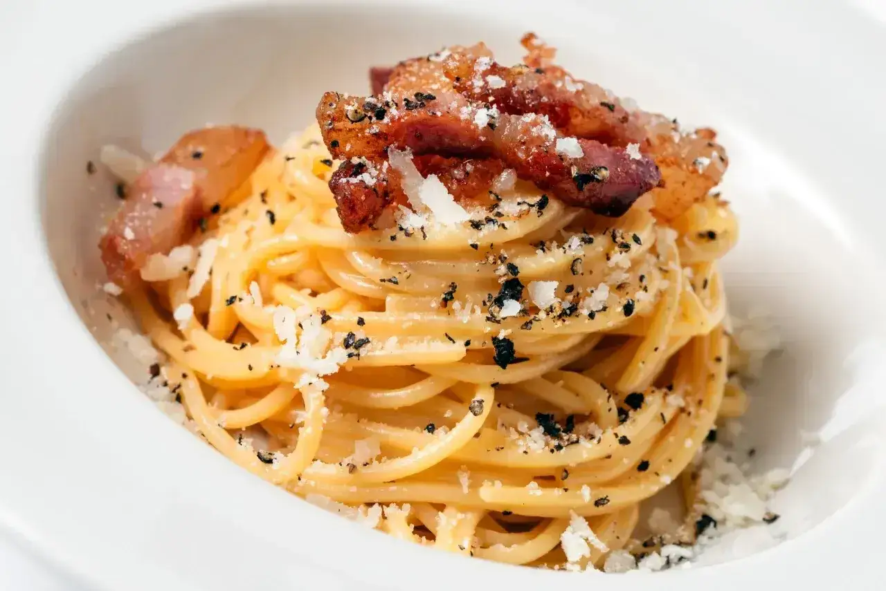 Pyszna carbonara z chrupiącym boczkiem, posypana parmezanem i pieprzem. Idealny boczek do carbonary to klucz do sukcesu.