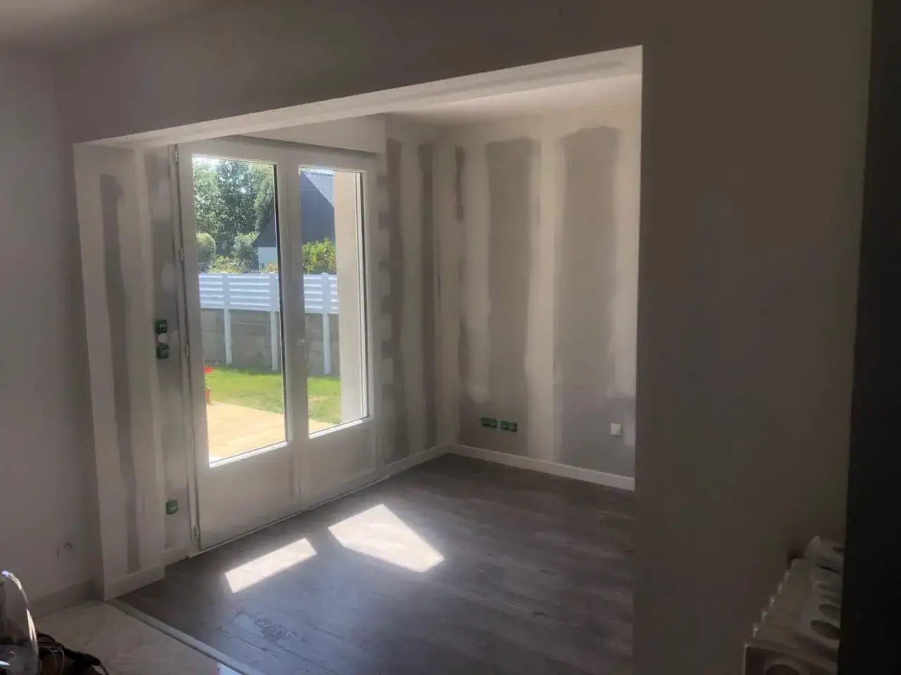 Aménagement en cours pour transformer un garage en habitation. Les murs sont prêts pour la peinture, le sol est posé.